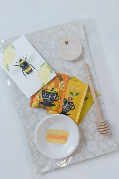 origineel cadeau voor theeliefhebber, pakketje met theetipje met macaron illustratie, honinglepel en verschillende theezakjes