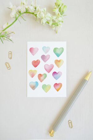blanco ansichtkaart met allemaal aquarel geschilderde hartjes in verschillende pastelkleuren