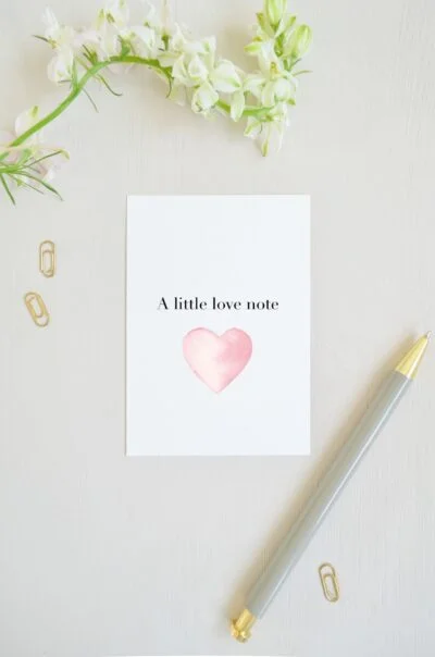 blanco ansichtkaart met groot roze hart van aquarel en op de voorkant de tekst 'a little love note', voor een klein liefdes briefje