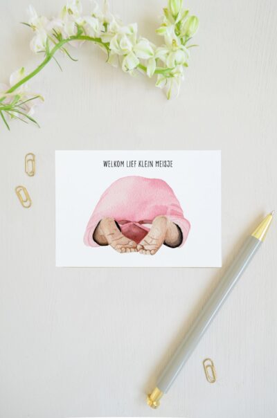 blanco ansichtkaart met babytje met roze rompertje, met focus op de babyvoetjes, geschilderd met aquarel en op de voorkant de tekst 'welkom lief klein meisje'